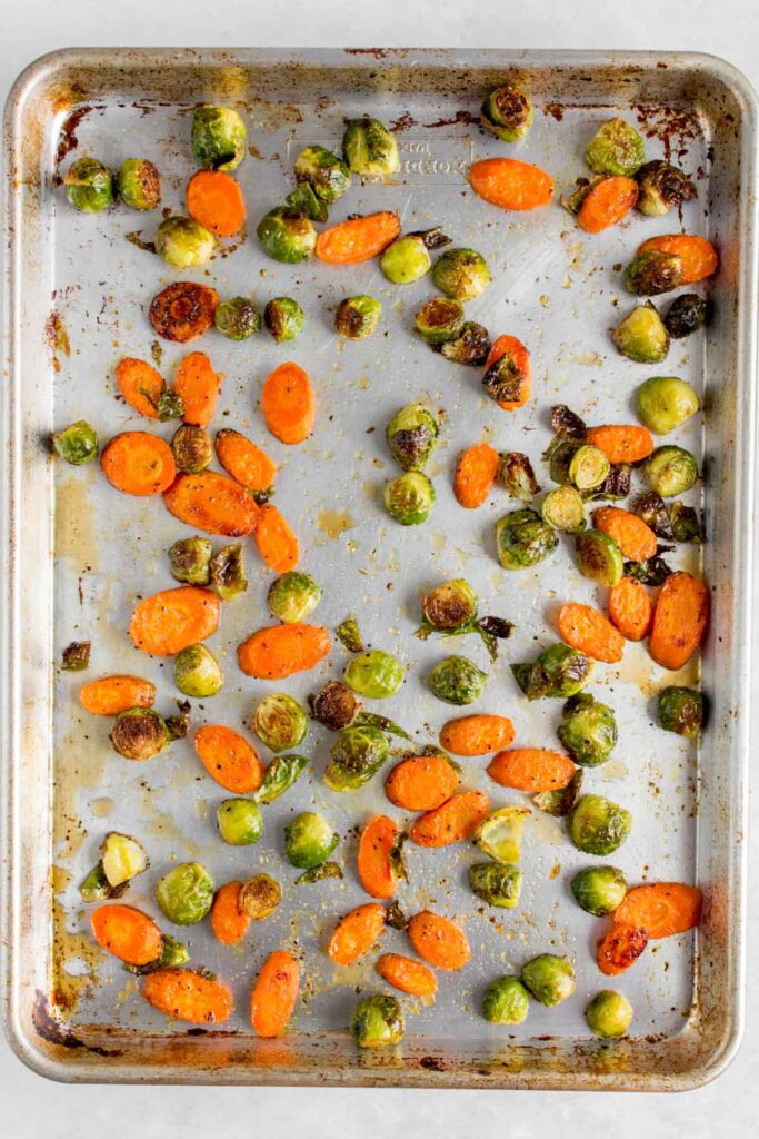 A pan of roasted brussels sprouts and carrots with maple glaze.