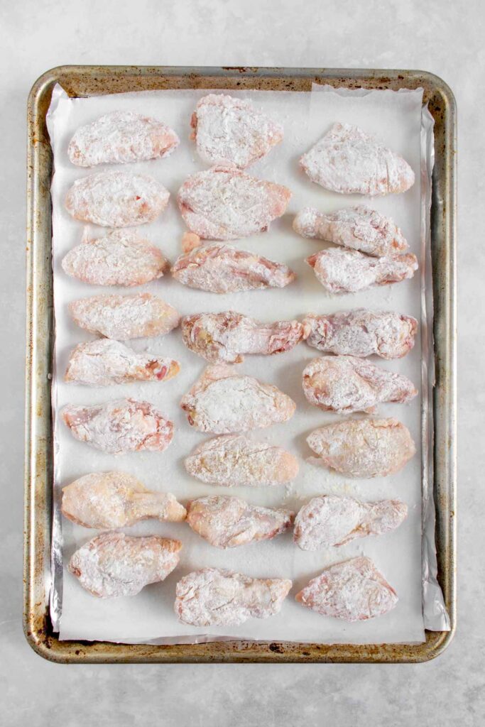 Potato starch coated wings lined on a sheet pan.