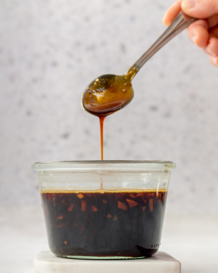 Teriyaki sauce dripping off a spoon into a jar.