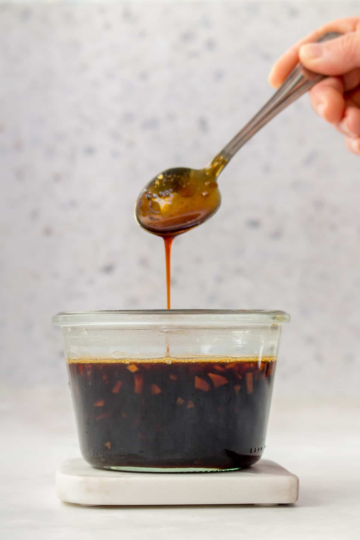 Teriyaki sauce dripping off a spoon into a jar.