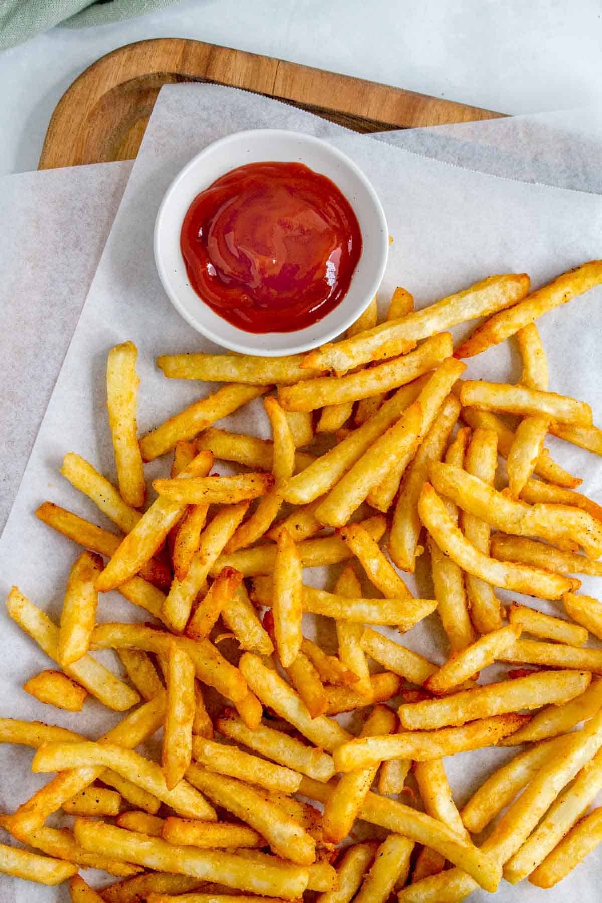 Air fryer frozen fries on a serving board with ketchup.