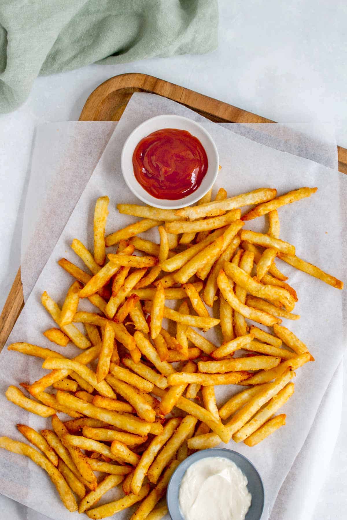 Air fryer frozen fries on a serving board with dipping sauces.