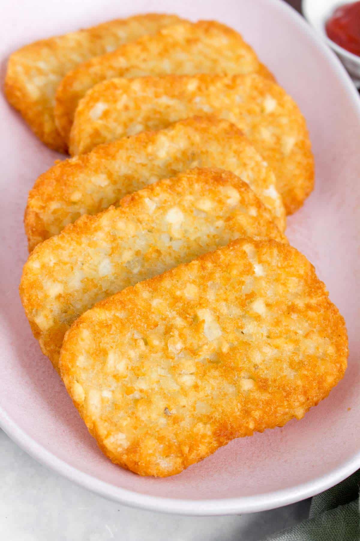 Overhead view of a pink platter of air fryer hash browns.