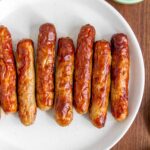 A plate with air fryer sausage links with maple syrup on the side.