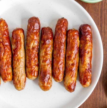 A plate with air fryer sausage links with maple syrup on the side.