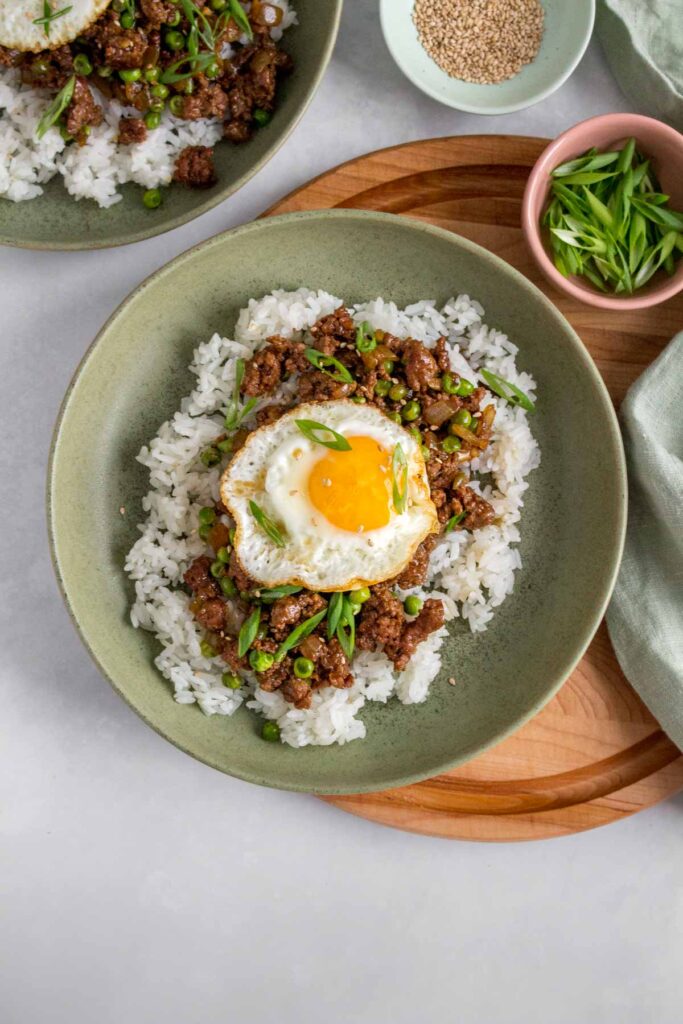 A bowl of rice with ground beef and fried egg on top.