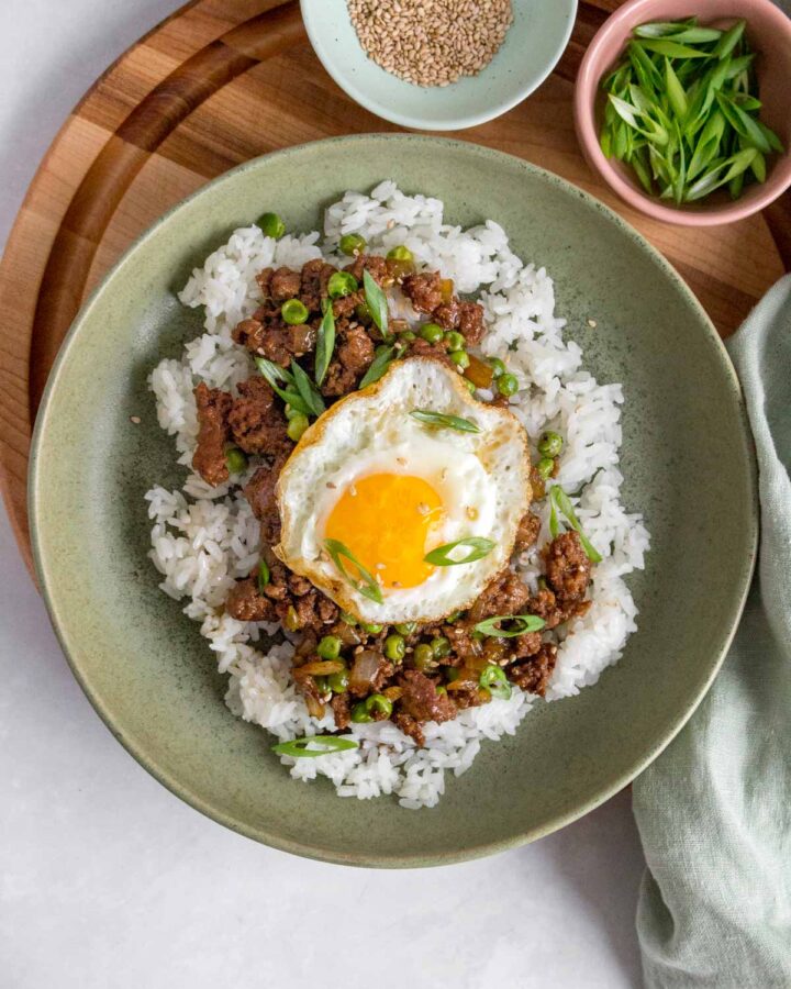 A bowl of rice with ground beef and fried egg on top.
