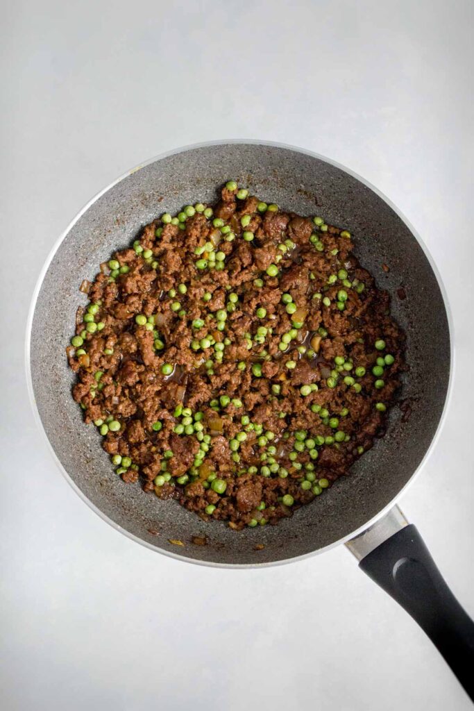 Cooked beef and peas in a pan.