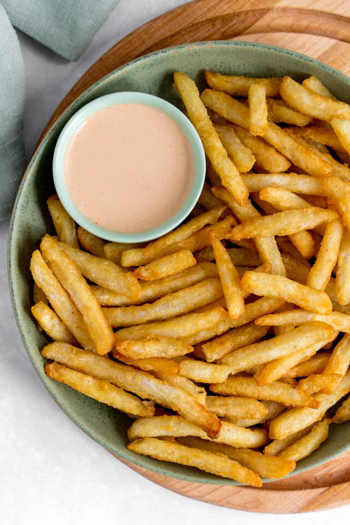 A plate of fries with a close up of a small dipping bowl of chipotle crema with lime.