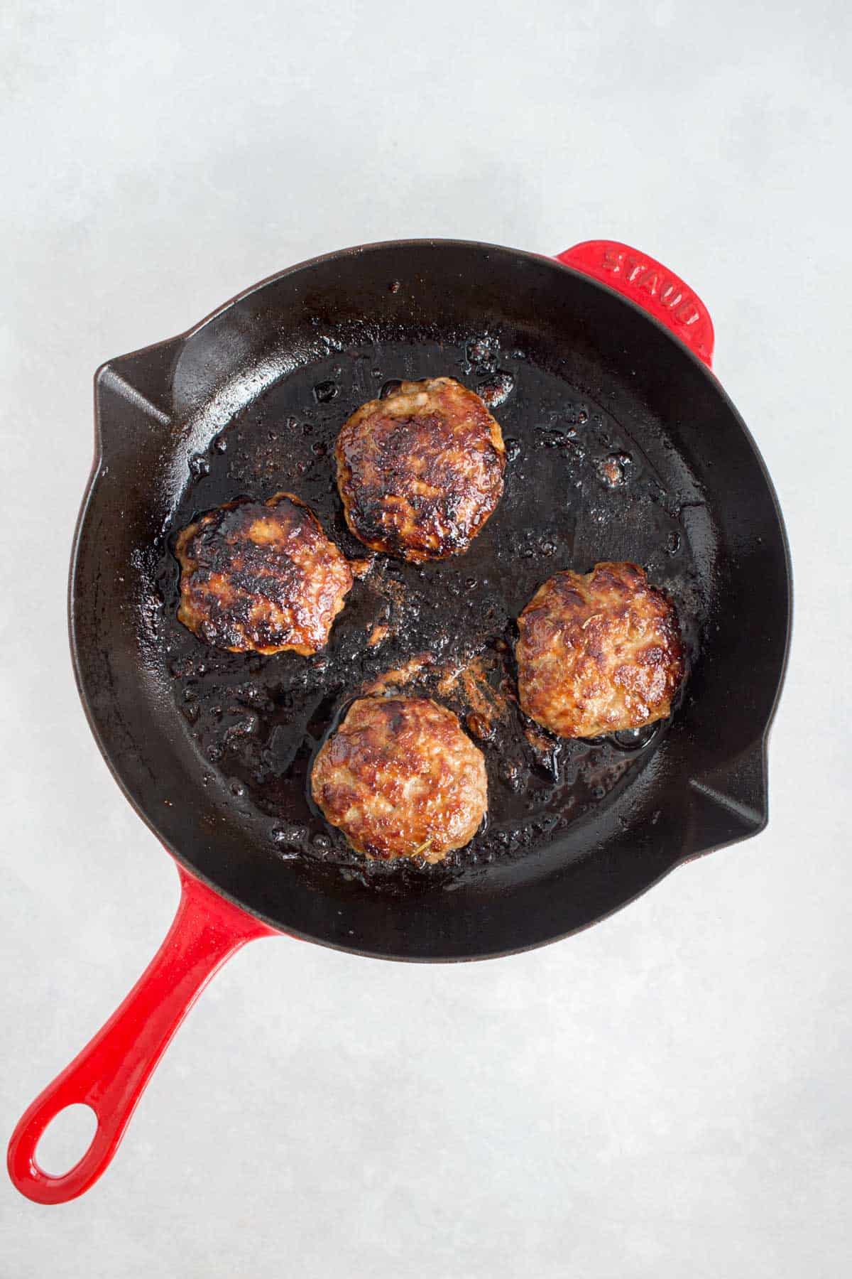 Sausage patties cooked in a cast iron pan.