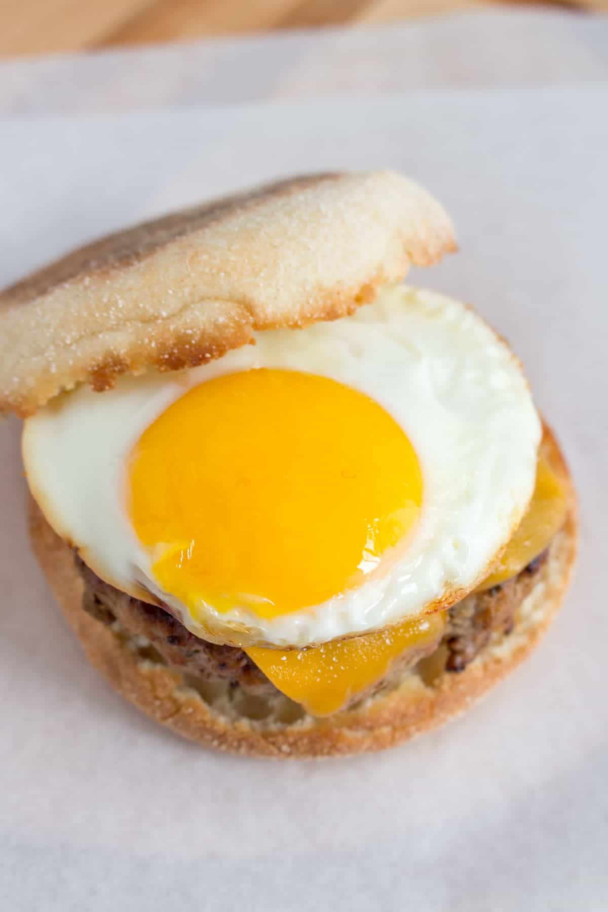 Overhead angled view of an sausage egg mcmuffin with the egg showing.