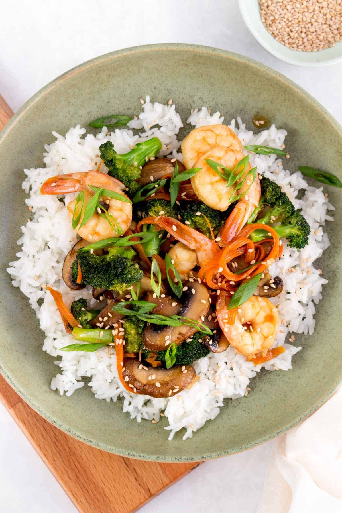 A bowl of rice with shrimp and broccoli on top.