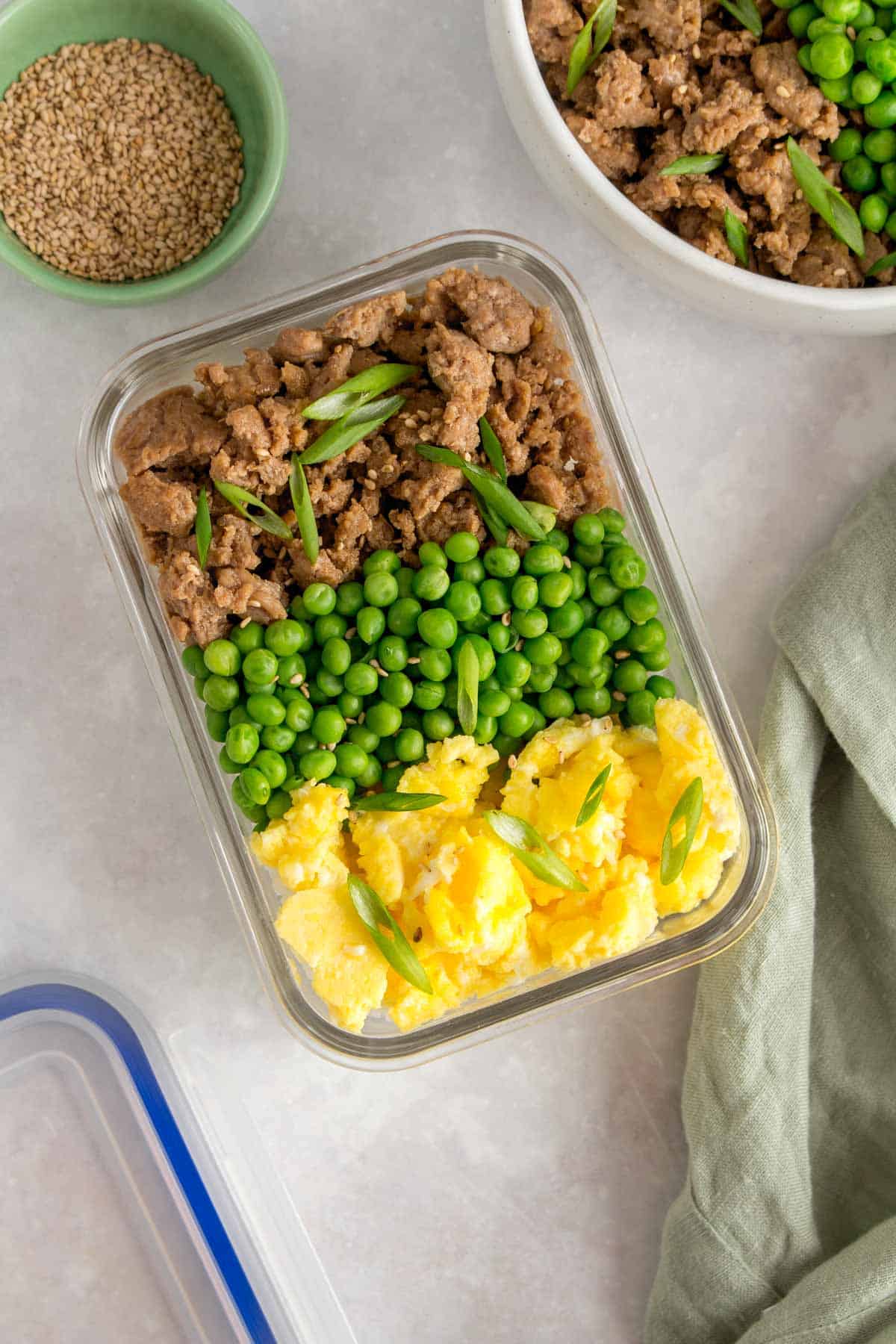 A meal prep container with rice, ground chicken, peas, and scrambled egg.