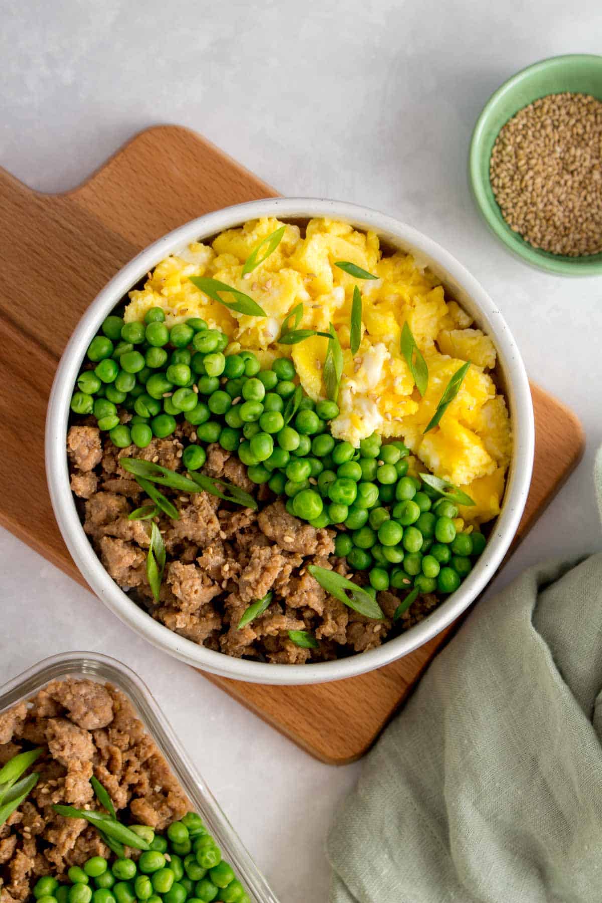 A bowl of rice with ground chicken, peas, and scrambled egg.