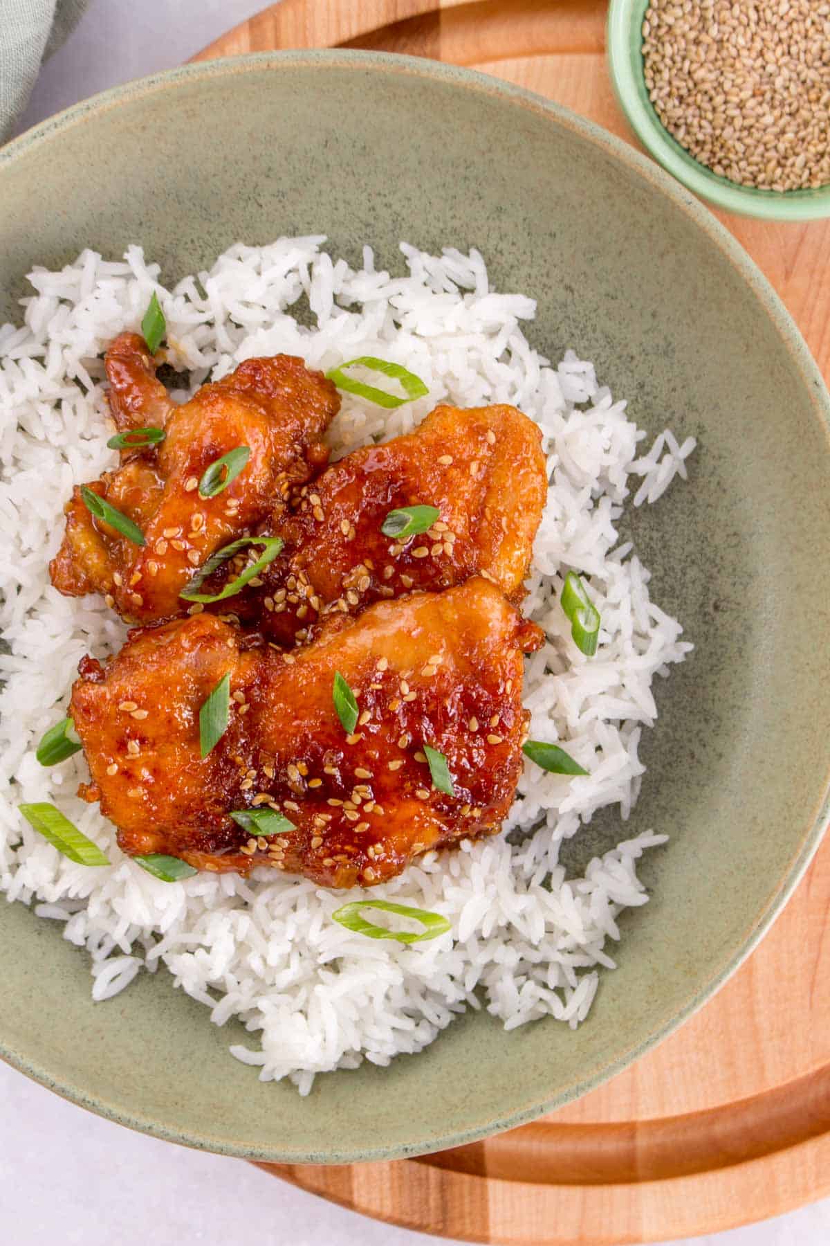 A plate of rice with honey sesame chicken on top.