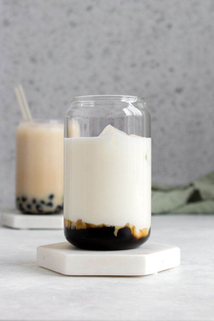 A glass with lychee milk and tapioca with brown sugar syrup.