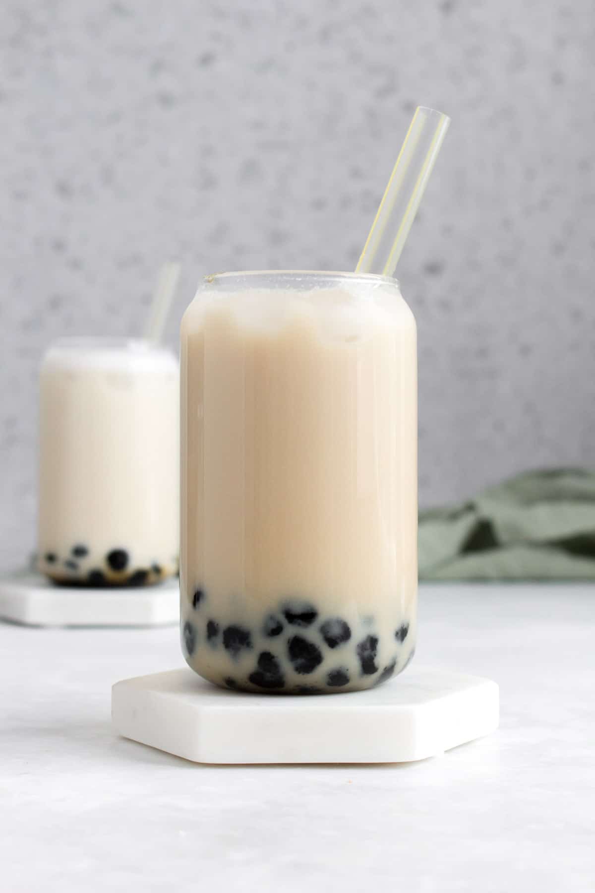 A glass of lychee bubble tea with a straw.