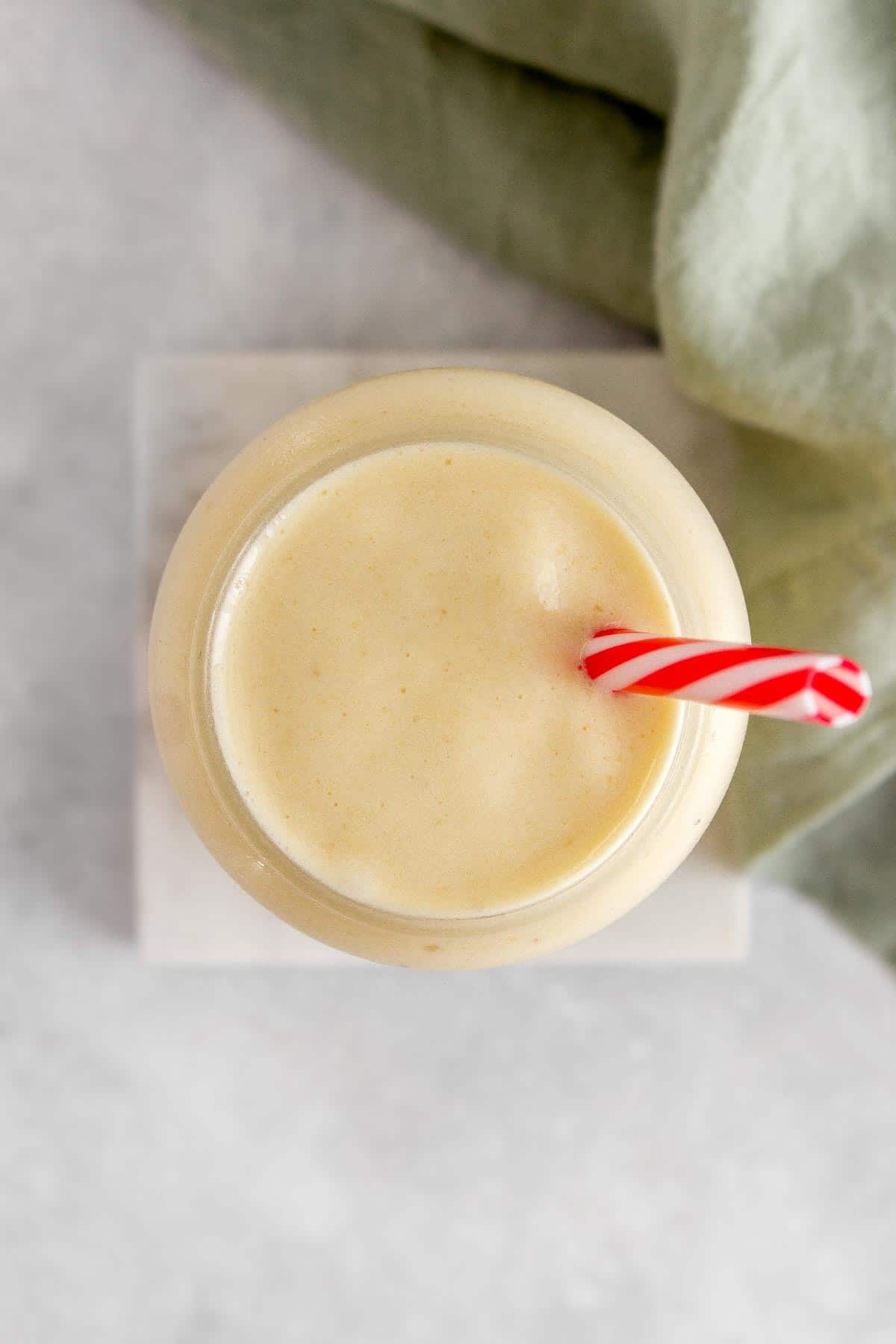 Overhead view of a glass of pineapple banana smoothie.