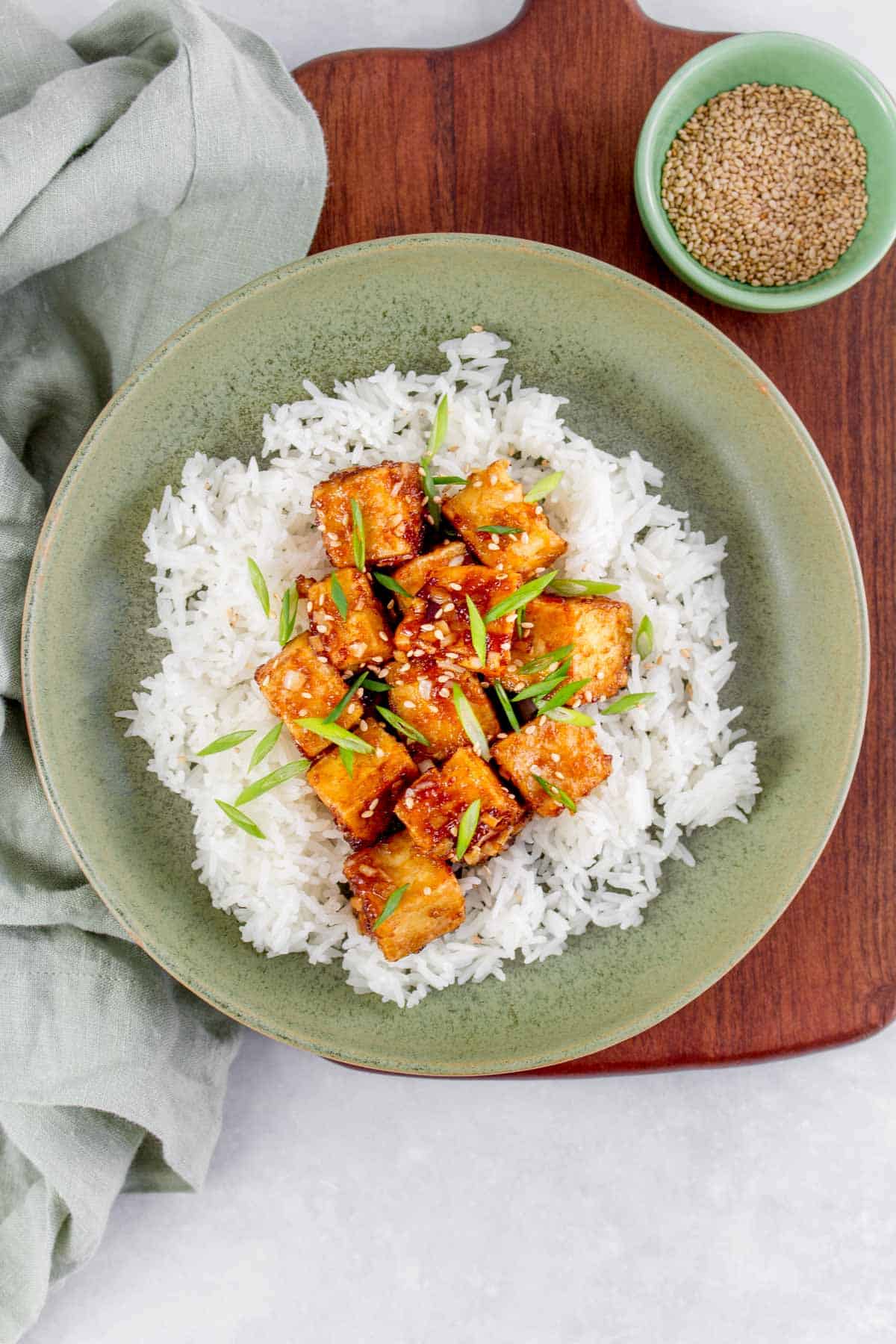 A bowl of rice with crispy pan fried sesame tofu on top.