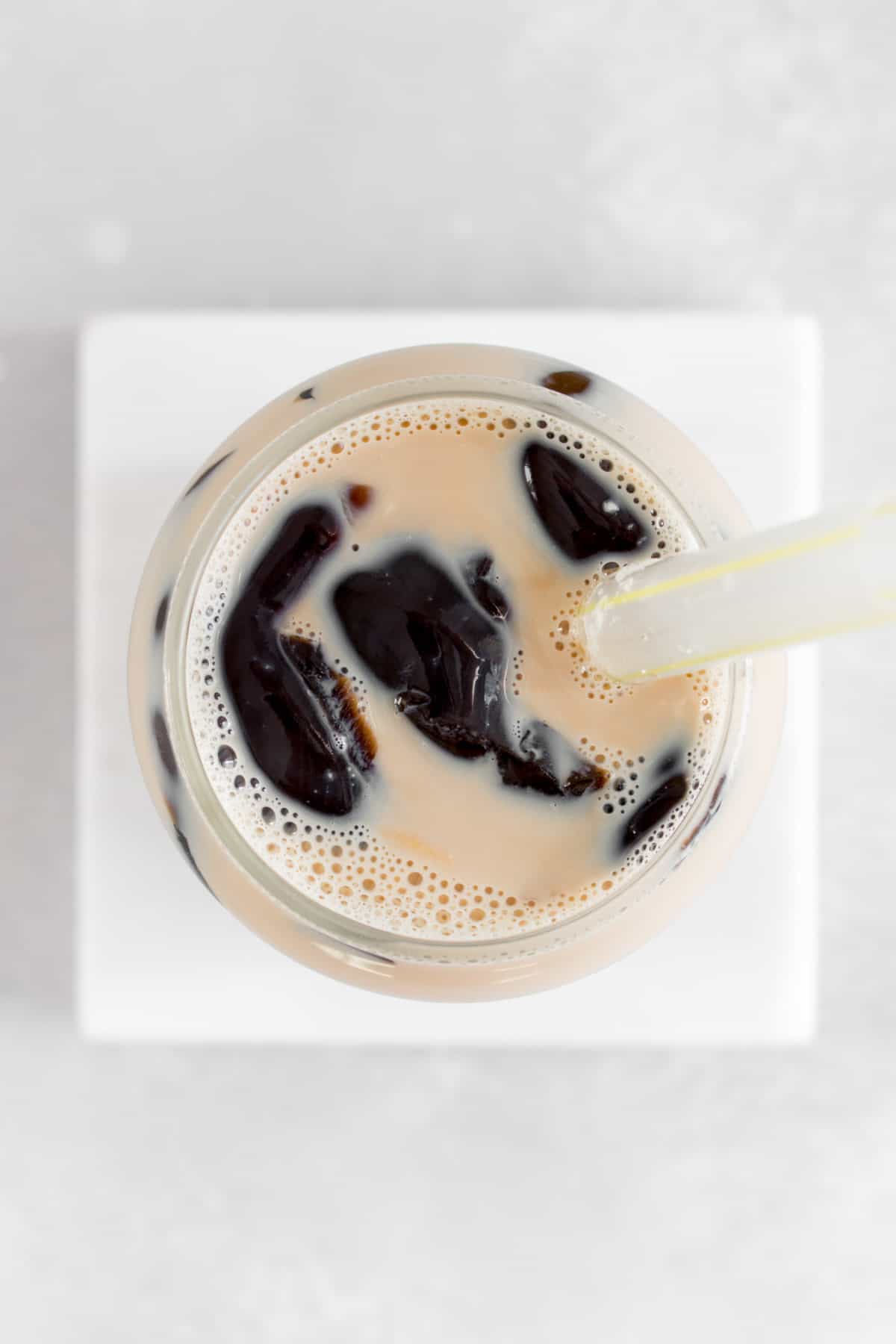 Overhead view of a glass of grass jelly milk tea.