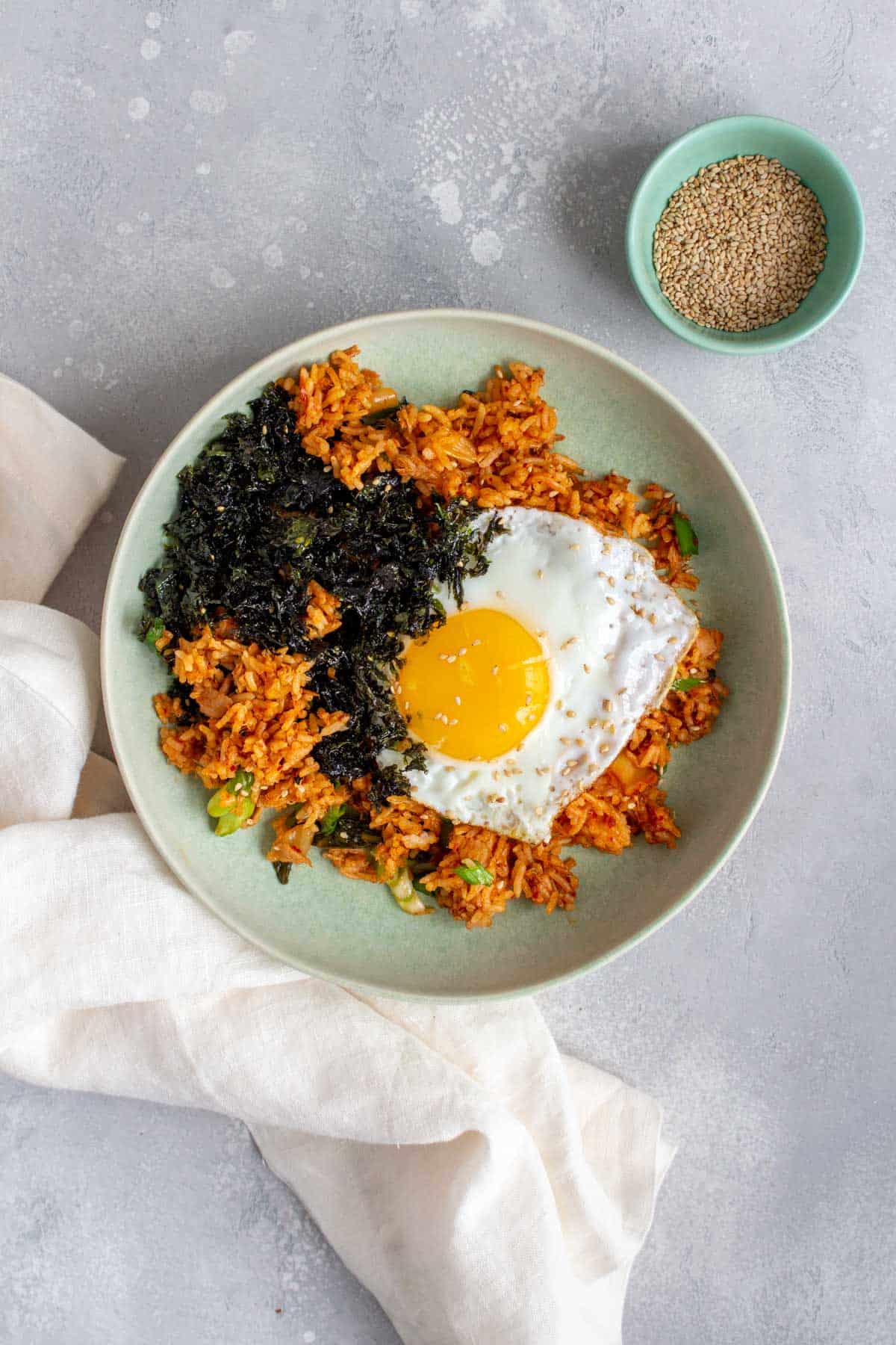 A bowl of tuna kimchi fried rice with a fried egg and shredded seaweed.