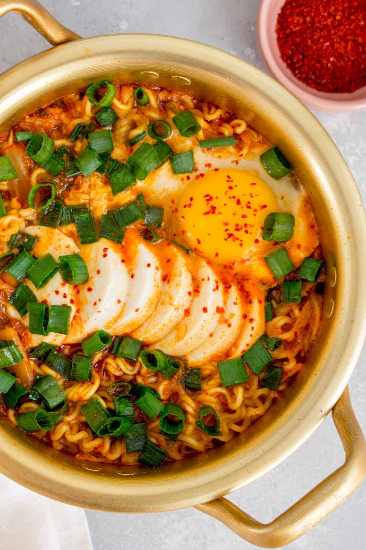 Overhead view of a pot of Korean instant noodles with soft tofu and egg.