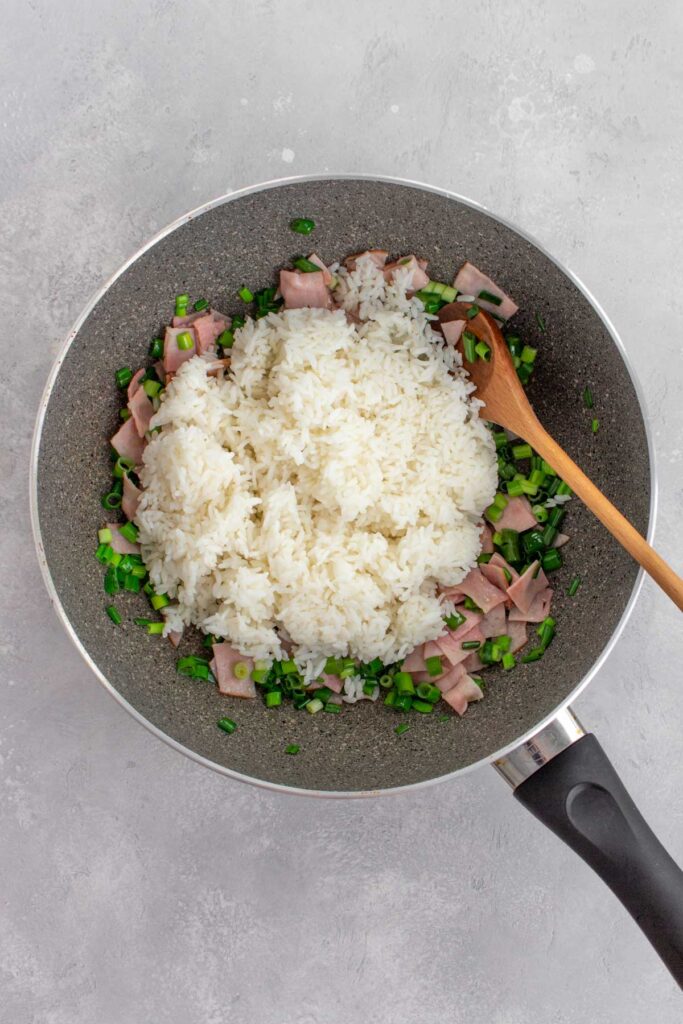 Cooked white rice added to a pan.