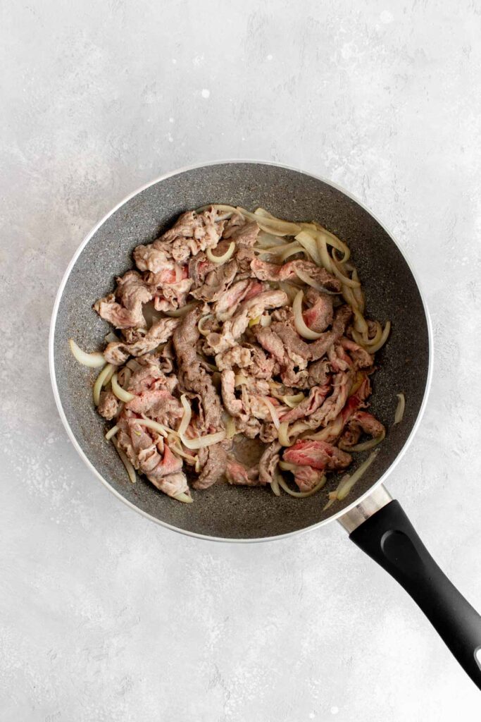 Beef sauteed in a skillet.