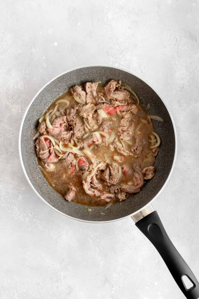 Sauce added to beef in a skillet.