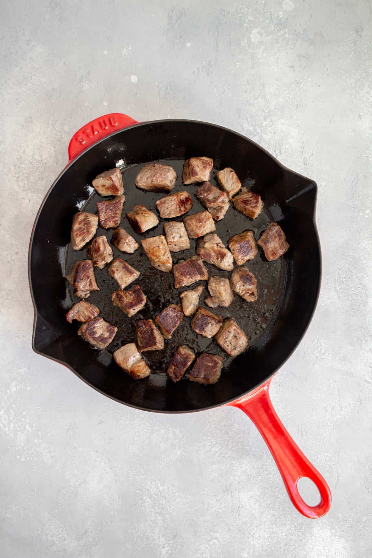 Seared steak cubes in a cast iron.