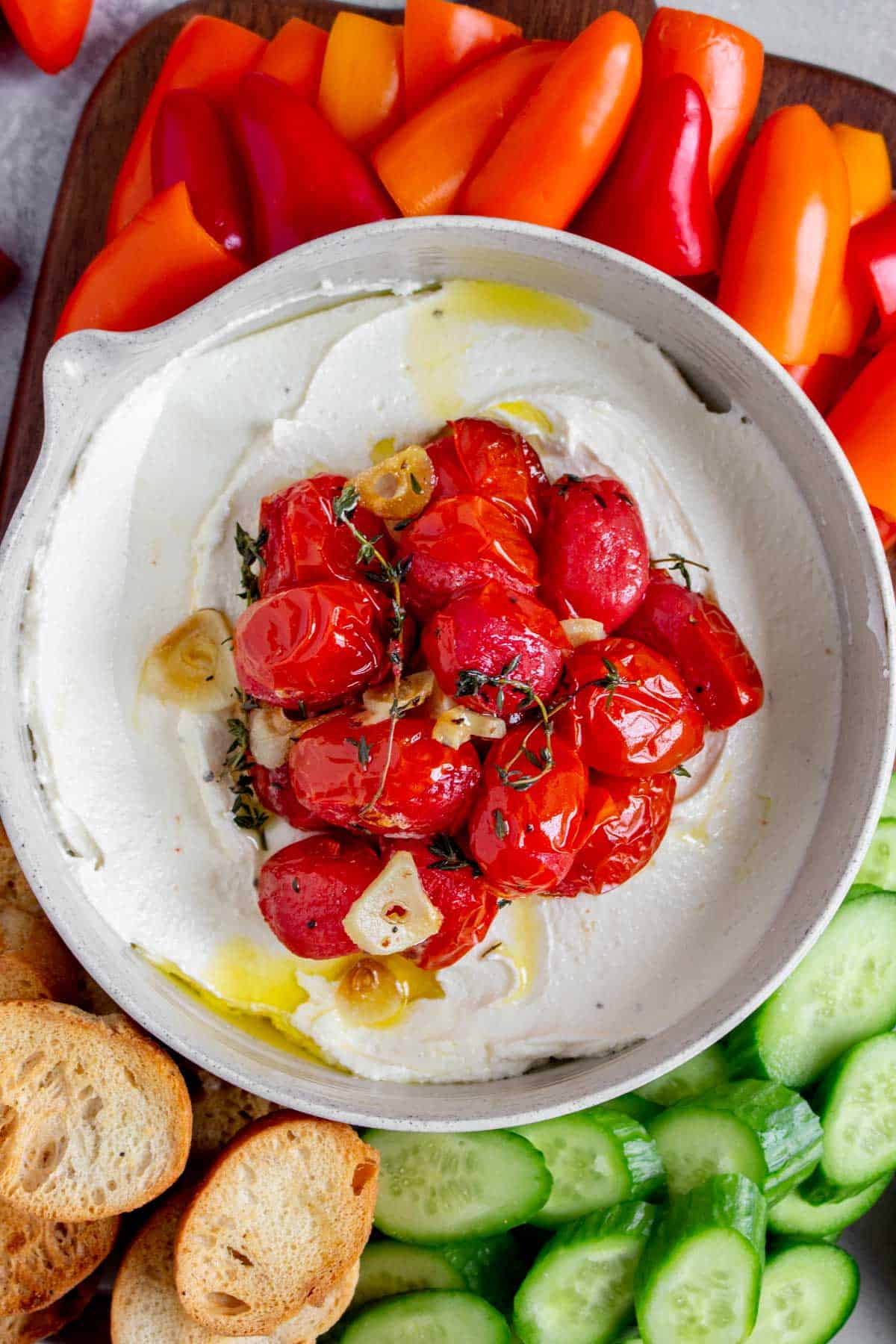 Close up of a bowl of whipped feta with roasted tomatoes on top.