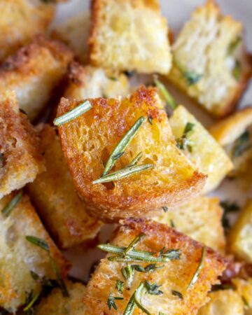 Close up of a golden air fryer crouton with rosemary on it.