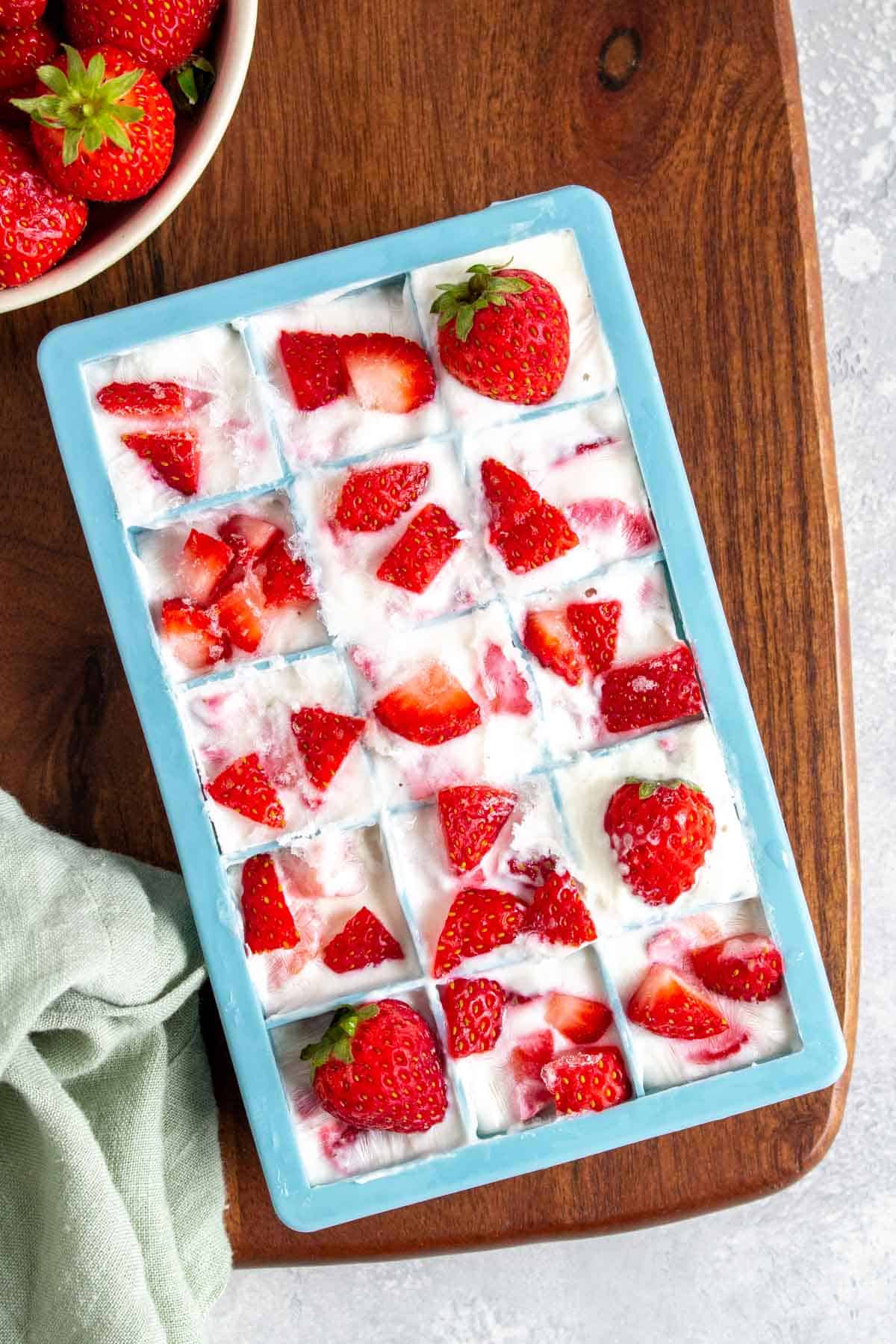 An ice cube tray filled with frozen strawberry yogurt cubes.