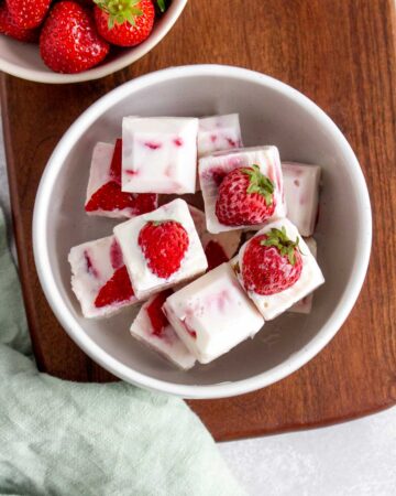 Overhead view of a bowl of frozen strawberry yogurt cubes.