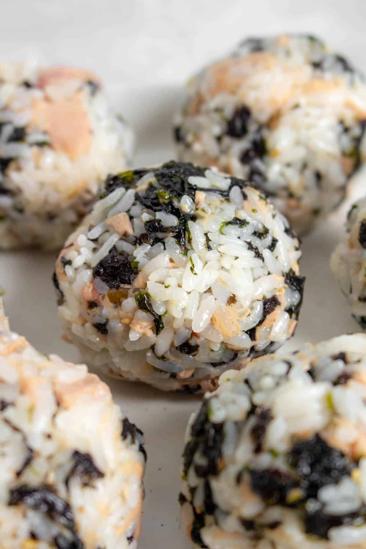 One tuna mayo rice ball in focus surrounded by more balls.