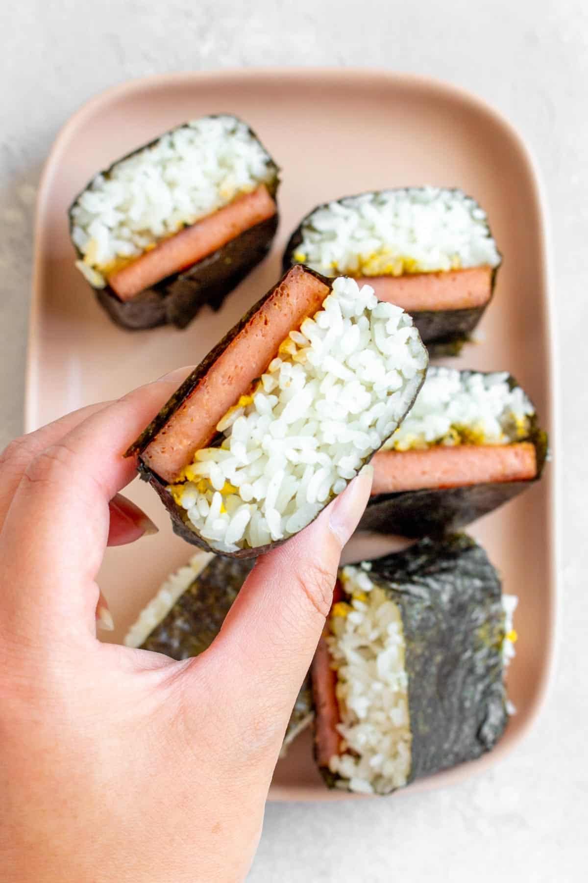 Hand holding a spam musubi. 
