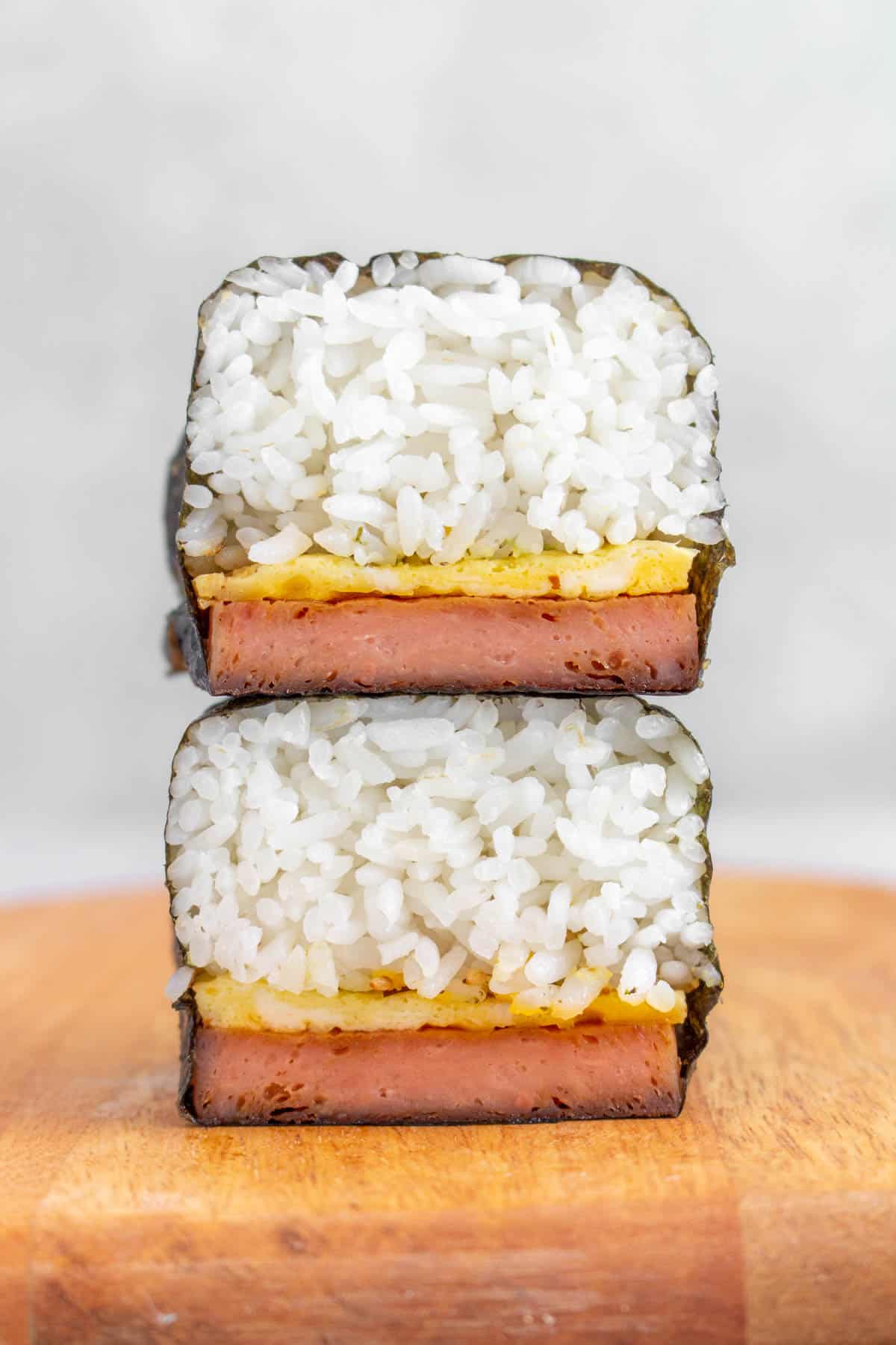Two pieces of spam musubi with egg stacked on top of each other.