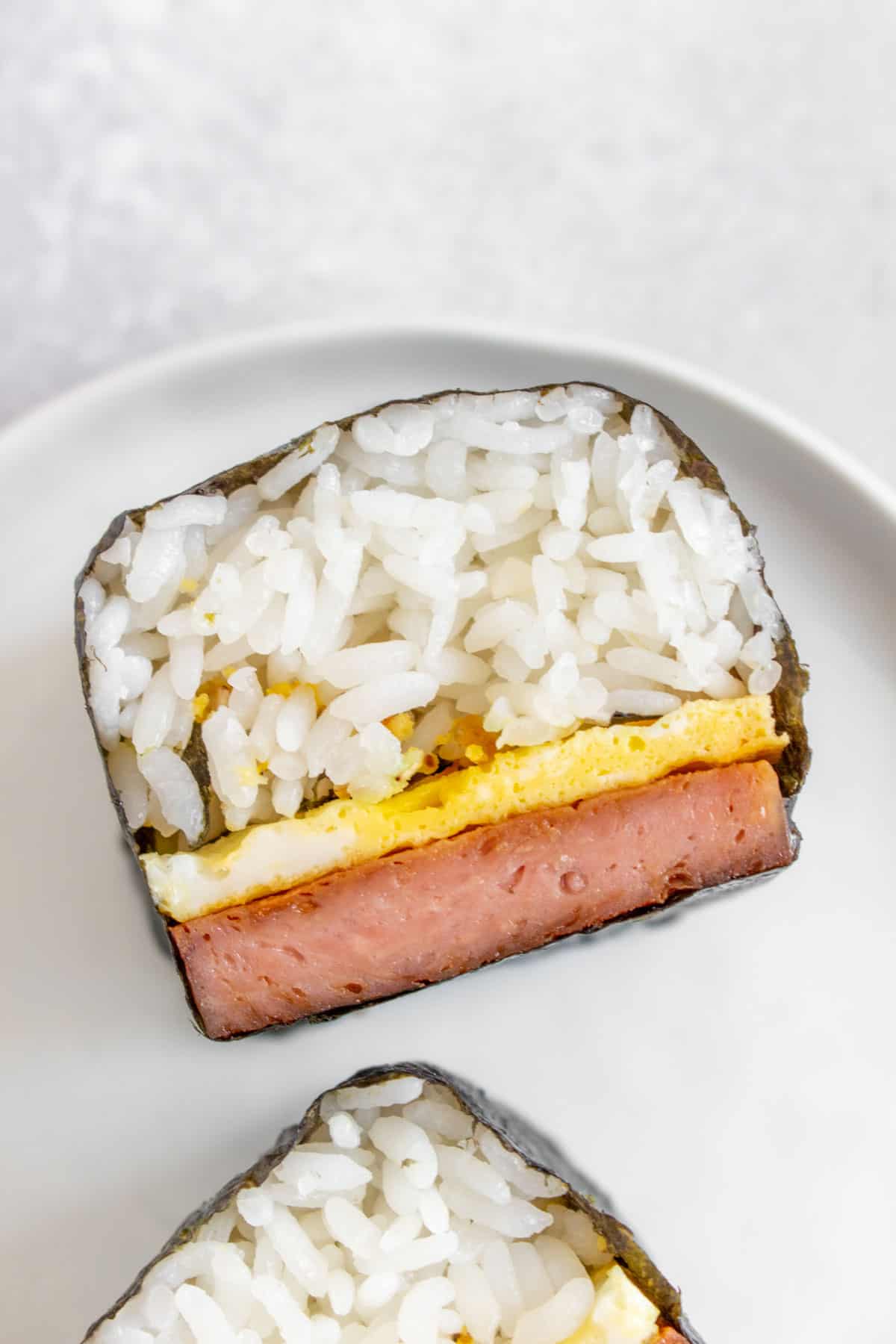 Overhead view showing the inside of a cut spam musubi with egg.