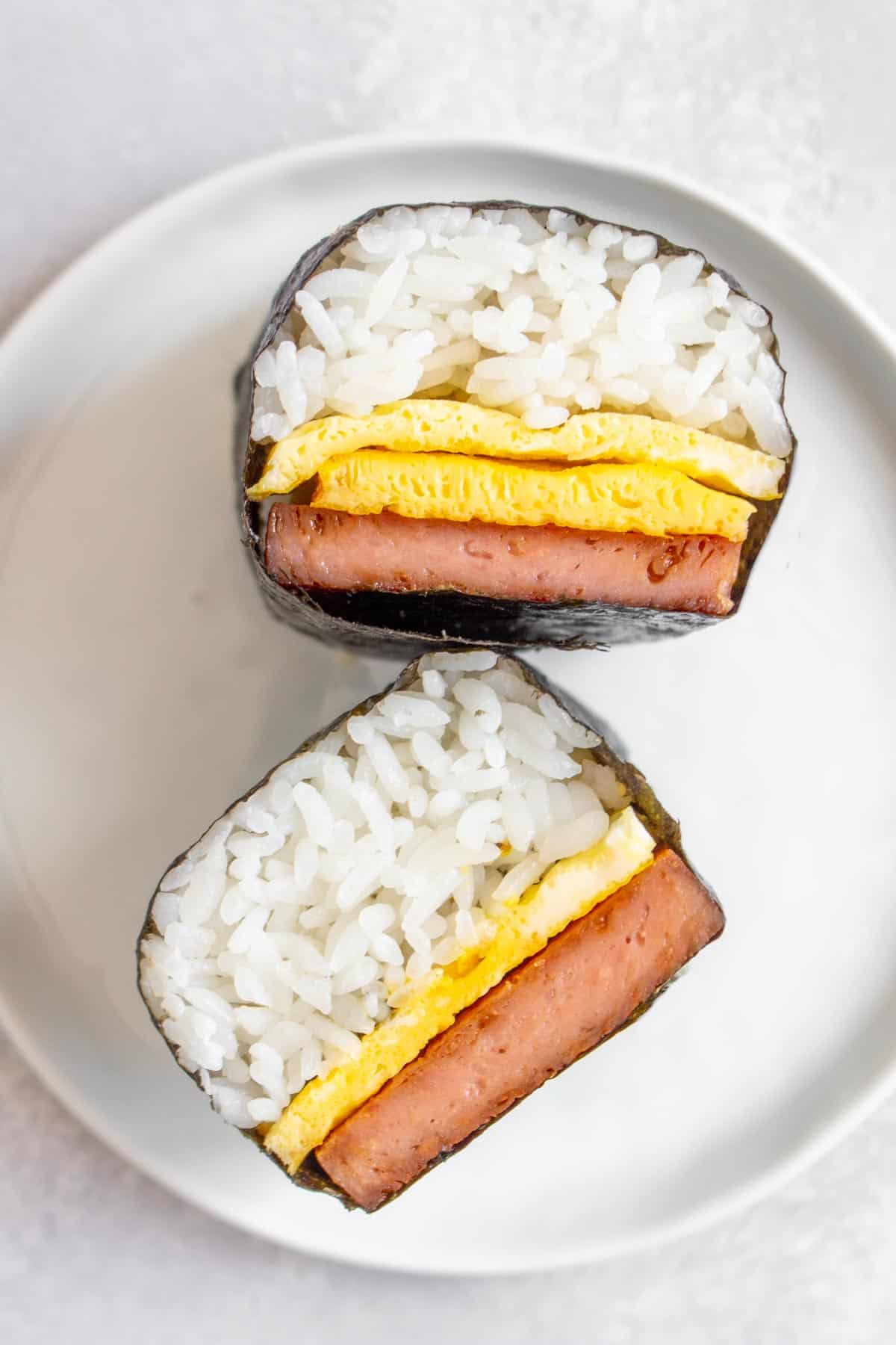Two pieces of spam musubi with egg, one with two layers of egg.