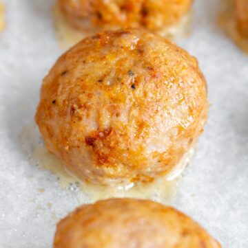 Close up of one of three baked turkey meatballs.
