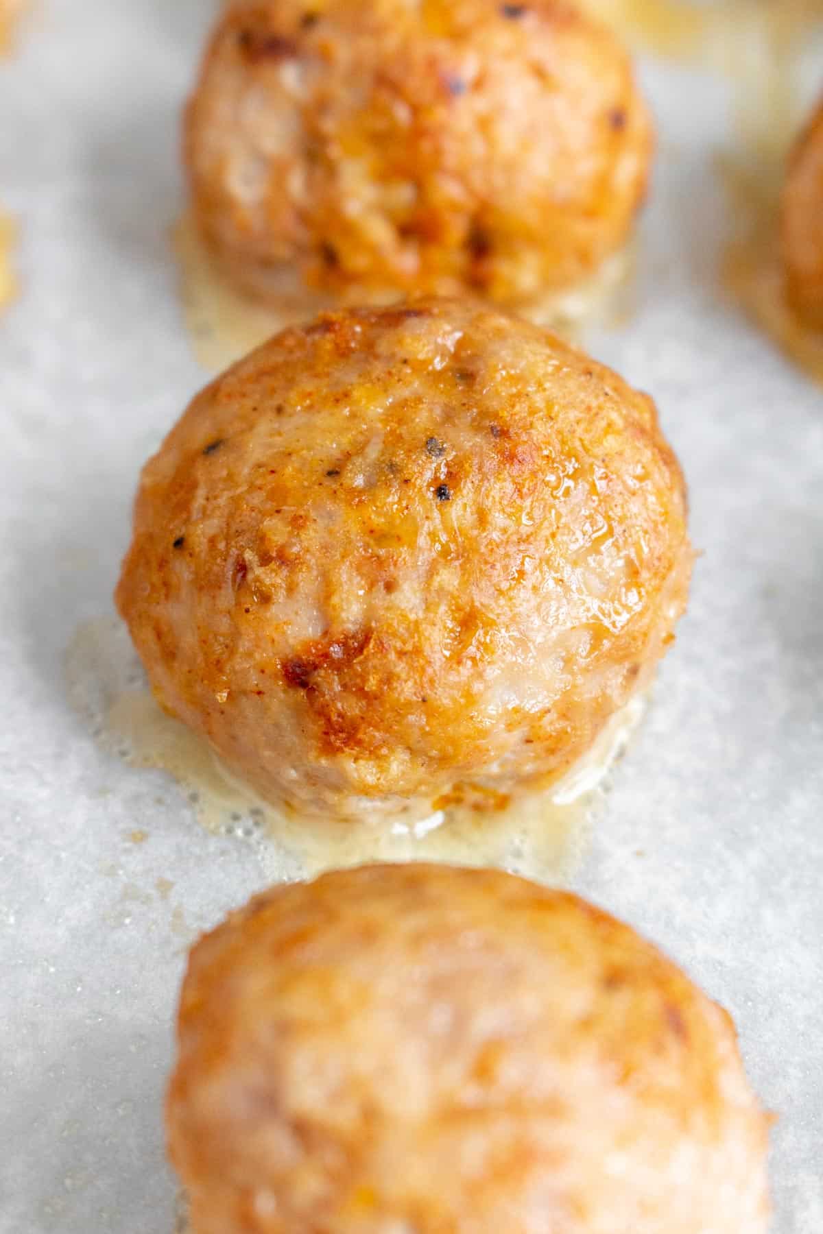 Close up of one of three baked turkey meatballs.