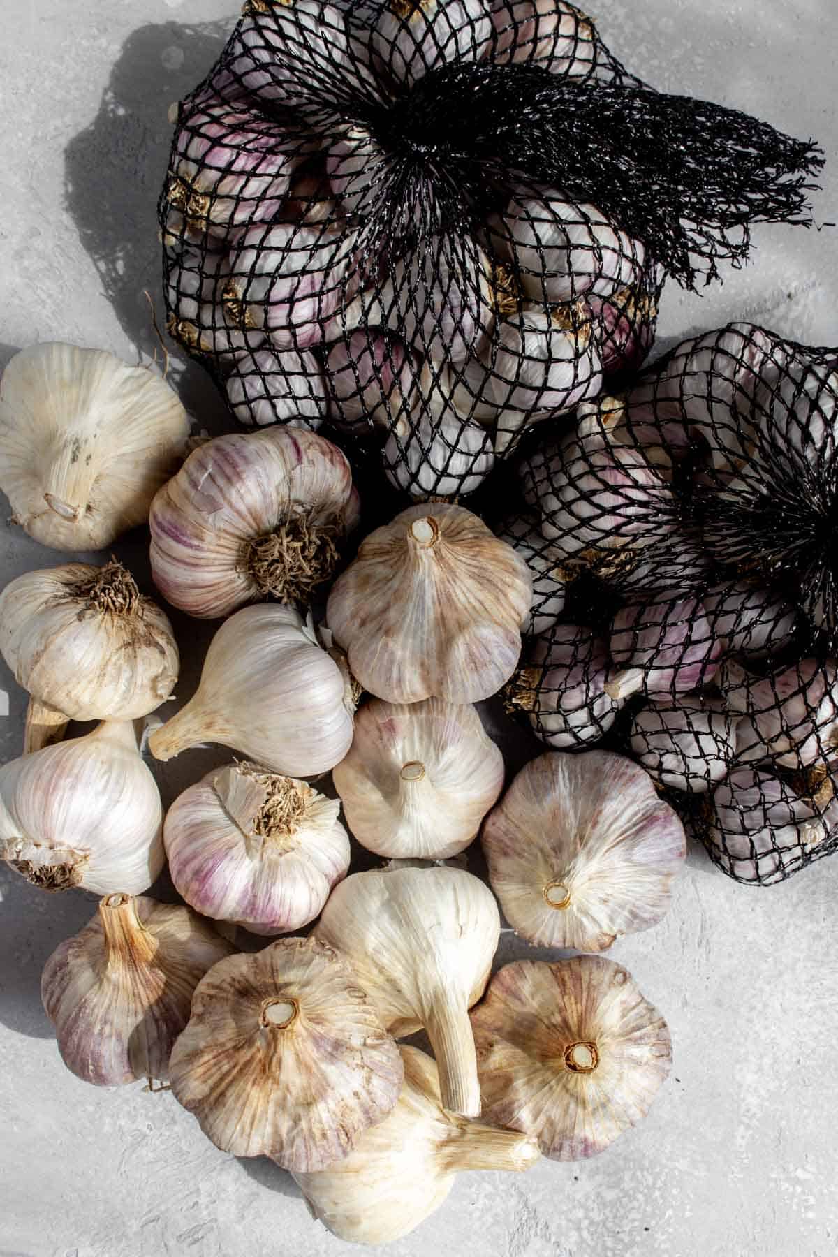 Multiple garlic in a pile, some in a bag.