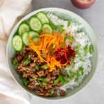 Overhead view of a Korean turkey bowl with cucumbers and carrots.