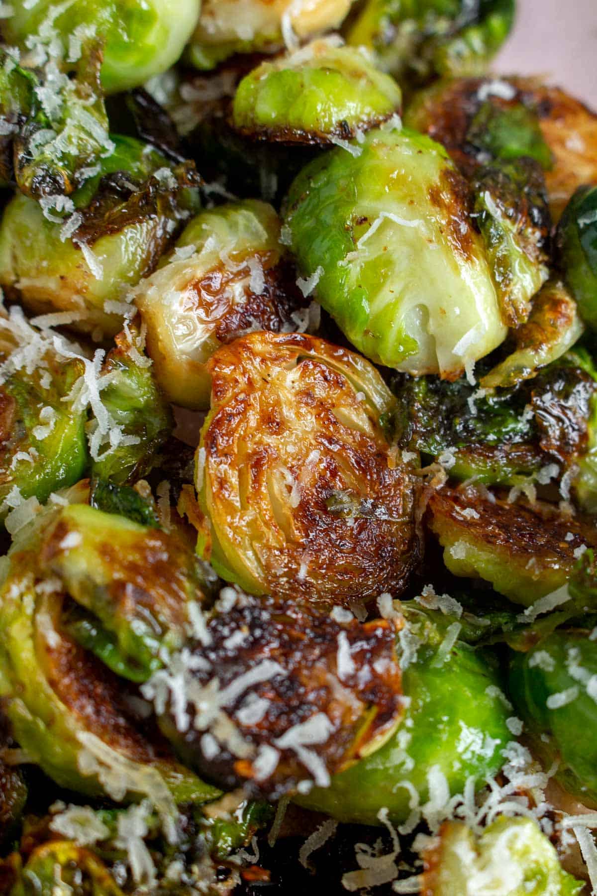 Close up of pan fried brussels sprouts with shaved parmesan on top.