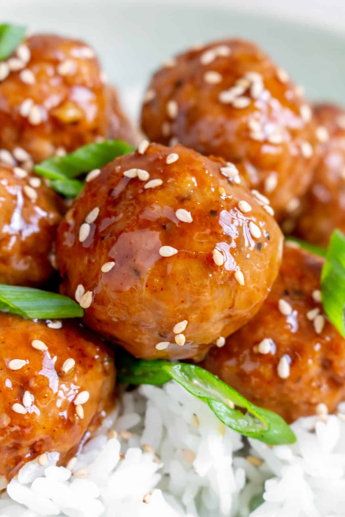 Close view of a teriyaki turkey meatball on top of rice.