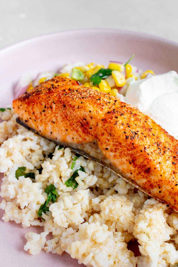 Profile view of an air fryer salmon fillet over a bed of cilantro lime brown rice.