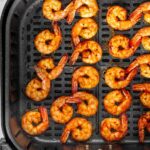 Overhead view of air fried shrimp inside an air fryer basket.