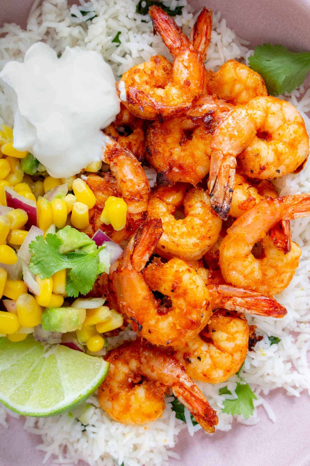 Close up of air fryer shrimp with rice, corn salsa, and sour cream.