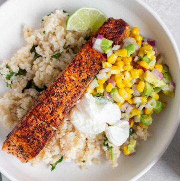 Overhead view of a plate of rice, corn salsa, sour cream, and salmon.