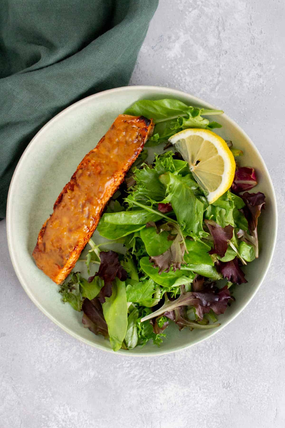 A plate with mixed greens and air fryer salmon with maple dijon.